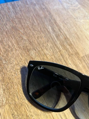 Svarta Ray-Ban boyfriend solglasögon - Klassiska svarta boyfriend solglasögon från Ray-Ban med ikonisk form och diskret logga på bågen. Snygg och tidlös design som passar till alla stilar. Bågarna är i plast och glasen är mörka för ett coolt uttryck.