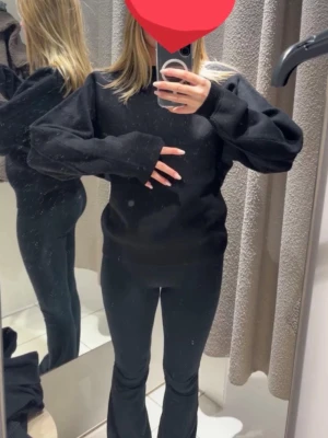 Svart stickad tröja - En svart stickad tröja med oversized passform och långa ärmar. Tröjan har en enkel design med rund halsringning och breda muddar. Perfekt för en avslappnad och trendig look.
