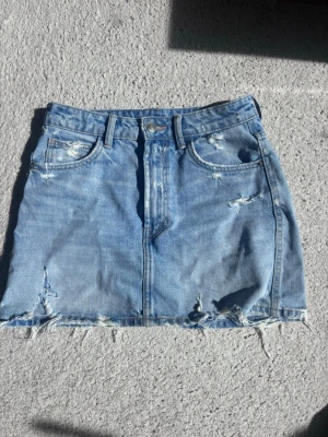 Ljusblå jeanskjol med slitningar - Jeanskjol från Zara i small. Enda skada är en reva på framsidan.. annars bra kvalitet! 