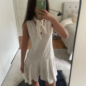  Prickig klänning - Söt vit kortklänning med svarta prickar och knyt i halsen. Klänningen är ärmlös och har en  utsvängd nederdel. Perfekt för sommaren❤️i väldigt bra skick och har inga defekter❤️pris kan diskuteras❤️Stockholmsstil