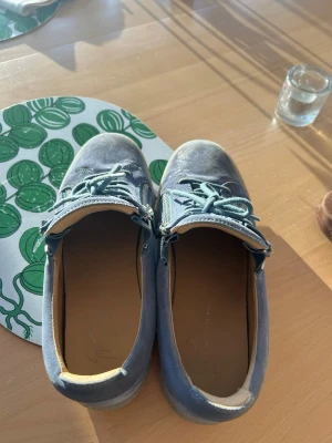 Guiseppe Zanotti - Snygga blå Guiseppe Zanotti sneakers i mocka med matchande skosnören och coola dragkedjor på sidorna. Skorna har en låg siluett och en tjock, mörk sula som ger en modern vibe. Perfekta för dig som gillar stilrena detaljer och vill ha något som sticker ut lite extra.