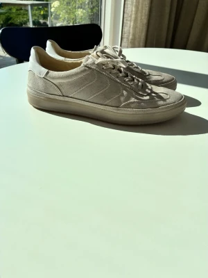 Vagabond mocka sneakers - Snygga beige sneakers från Vagabond i mocka med vita detaljer och klassisk låg profil. Skorna har vita snören och en diskret sula i gummi. Perfekta för en clean och somrig samt stilren look. Hör av dig om frågor och priset ej hugget i sten! 😊
