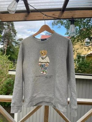 Grå sweatshirt Polo Bear Ralph Lauren - Säljer denna fina polo bear tröjan från Ralph Lauren storlek XL/18-20 i barn storlek vilket motsvarar XS-S i vuxenstorlek. Inga skavanker, Går ej att få tag på i Sverige då den är köpt i USA. Kvitto finns.