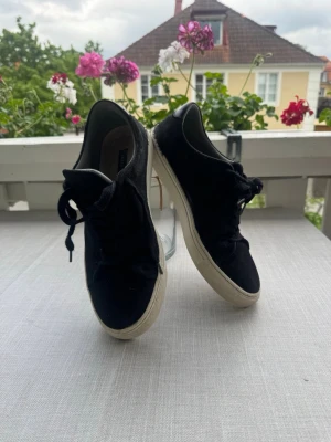 Svarta sneakers med vit sula - Stilrena svarta sneakers med klassisk vit sula och svarta skosnören. Ovandelen är i mocka material och modellen är låg.