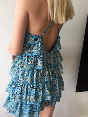 Snyggaste volangklänningen turkos med guld inslag - Riktigt snygg mini klänning med volanger! Mycket eftertraktad! Sommarens måste plagg i garderoben! Populär sommar färg turkos med guldiga inslag. Klänningen är i topp skick. Jag är en strl S