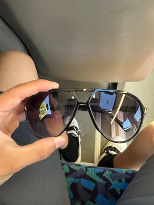 Svarta aviator solglasögon - Snygga svarta aviator solglasögon från Tom Ford med mörka glas och klassisk metallbåge. De har en ikonisk T-detalj i silver på sidorna och ger en cool vibe till din stil.