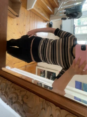 Randig stickad tröja i svart och beige - Snygg stickad tröja med svarta och beigea horisontella ränder. Tröjan har rund halsringning, korta ärmar och ribbade muddar. 