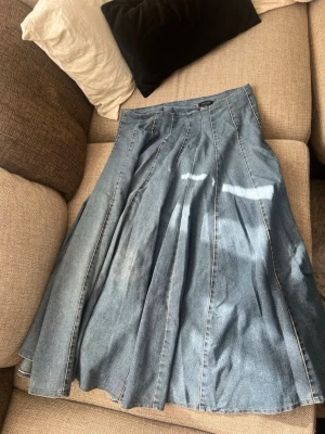 Lång jeanskjol med utställd passform - Snygg lång jeanskjol i blå denim med utställd siluett och markerade sömmar. Kjolen har klassisk midja och flera paneler som ger ett coolt fall. Perfekt för dig som gillar en avslappnad men trendig stil. Stor i storlek 