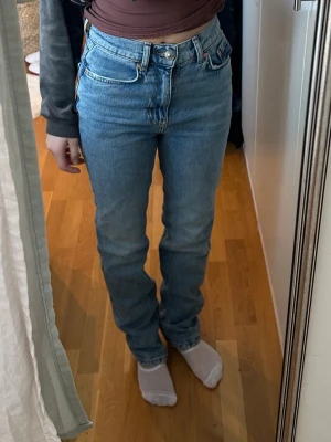 Blå raka jeans från Gina tricot - Säljer ett par klassiska blå raka jeans från gina tricot med hög midja och femficksmodell. Jeansen har en tidlös tvätt och är gjorda i slitstark denim. Perfekta för dig som gillar en enkel och clean look.