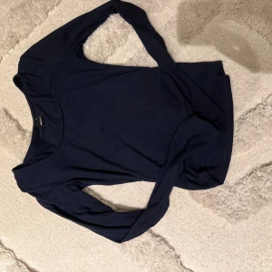 Mörkblå långärmad topp Gina Tricot - En enkel och stilren mörkblå långärmad topp från Gina Tricot. Toppen har rund halsringning och är tillverkad i ett mjukt material som känns skönt mot huden. Perfekt att matcha med jeans eller kjol för en clean look.