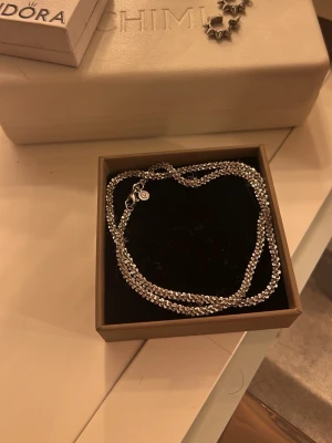 Silverfärgat halsband med pärldetaljer - Snyggt edblad halsband i silverfärg med små pärlliknande detaljer som ger ett glittrande intryck. Kedjan är tunn och flexibel, perfekt för att lyfta vilken outfit som helst. Levereras i en stilren ask.