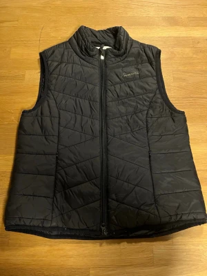 Svart dunväst från EST - Snygg svart rid dunväst från EST med dragkedja framtill och två sidofickor. 