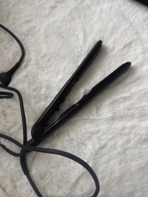 Svart plattång från OBH Nordica - Säljer en svart plattång från OBH Nordica med sladd. Plattången har en smal och stilren design i matt svart plast och är perfekt för att styla håret rakt eller vågigt. Enkel att använda och passar de flesta hårtyper.