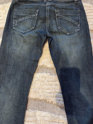 Mörkblå  jeans med slitningar🙏🏼 - Snygga mörkblå jeans med raka ben och diskreta slitningar framtill. Klassisk femficksmodell med kontrastsömmar och metallknappar. Jeansen har en cool tvättad look och passar perfekt till en avslappnad stil. Midjemåttet är 36 cm rakt över och innerbenslängden är 83 cm!