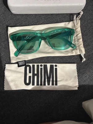 Gröna solglasögon från CHIMI - Snygga solglasögon från CHIMI i transparent grön plast med klassisk, något fyrkantig form. Kommer med originalfodral och putsduk. Perfekta för att addera färg till din look och skydda ögonen mot solen.modell modell 007 färg AQUA