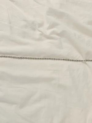 Silverfärgat tvinnat halsband - Säljer ett stilrent halsband i silverfärg med tvinnad kedja. Halsbandet har en enkel och klassisk design som passar till många olika stilar. Perfekt för dig som gillar minimalistiska accessoarer.