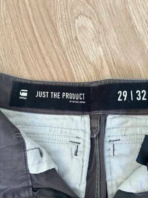 Grå cargobyxor från G-Star RAW - Snygga grå cargobyxor från G-Star RAW med flera fickor, bland annat en med dragkedja på benet. Byxorna har raka ben och klassisk cargomodell med robust känsla. Perfekta för dig som gillar streetwear och funktionella detaljer.