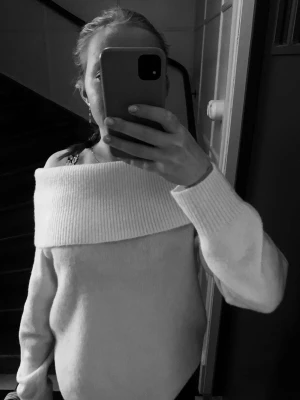 Offshoulder stickad tröja i cremevit - Säljer en snygg offshoulder stickad tröja i cremevit färg. Tröjan har bred ribbad krage som går över axlarna och långa ärmar med ribbade muddar. Perfekt att matcha med jeans för en chill look. Tröjan är lite nopprig men inget man tänker på. Storlek S men skulle mer säga en M