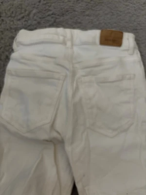 Vita jeans från Perfect Jeans - Säljer ett par vita jeans från Perfect Jeans med klassisk femficksdesign och dragkedja framtill. Jeansen har raka ben och är tillverkade i ett slitstarkt bomullsmaterial. Perfekt för dig som vill ha en clean och stilren look.