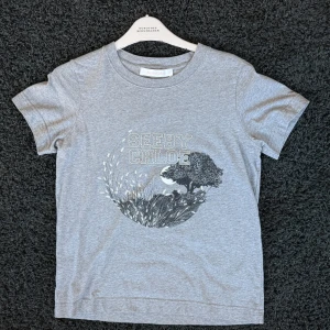Grå t-shirt från See By Chloé - Snygg grå t-shirt från See By Chloé med tryck och logga framtill. Tillverkad i mjuk bomull för en bekväm känsla. Storlek M men passar som en S skulle jag säga