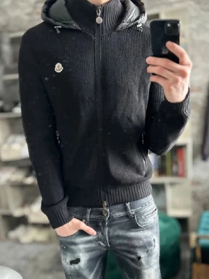 Svart Moncler jacka  - Säljer en svart jacka från Moncler med ribbstickad struktur, hel dragkedja framtill och justerbar huva med snören. Hoodien har ett Moncler-märke på bröstet och breda muddar vid ärmslut och midja. Perfekt för dig som gillar streetwear och exklusiva detaljer. Priset går att diskuteras vid snabb affär 🤑