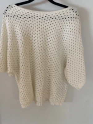 Vit oversize stickad tröja - Vit stickad tröja med oversize passform och hålmönster. Tröjan har bred halsringning och trekvartsärmar. 