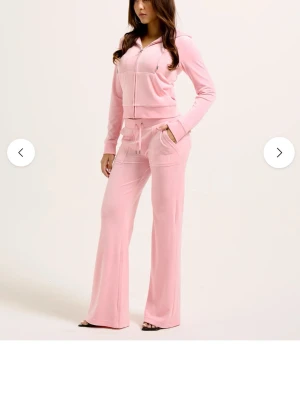 Rosa set Juicy Couture - Mysigt rosa set från Juicy Couture i mjukt material. Setet består av en zip-hoodie med fickor och matchande byxor med dragsko och vida ben. Perfekt för chill dagar hemma. Finns både tröja och byxor, går att köpa en av delarna hör av dig isåfall. Kan även skicka bilder hur det ser ut på men byxorna är lite stora för mig så kommer inte se lika bra ut på mih tyvärr🩷Byxor i L och tröja i M. Pris ej hugget i sten, priset är för båda så billigare vid köp av ett plagg. 