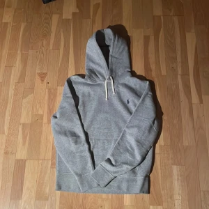 Grå hoodie från Polo Ralph Lauren - Säljer en stilren grå hoodie från Polo Ralph Lauren med klassisk logga på bröstet. 
