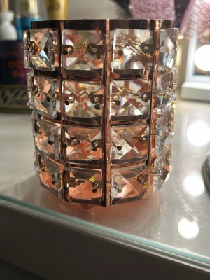  sminkborstganisör med kristaller - Unikt bredd sminkborstorganisör i roséguld med stora fyrkantiga klara kristaller i rutmönster. Sminkborstorganisören har en metallbas och gnistrar snyggt i ljuset. Perfekt statement piece för dig som vill sticka ut och addera lite extra bling till din look.