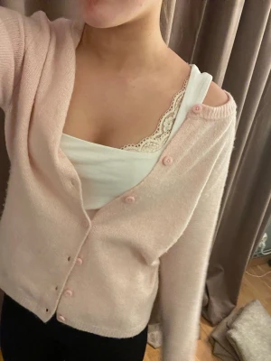 Ljusrosa kofta med knappar - Söt ljusrosa kofta med rund halsringning och matchande knappar framtill. Koftan har en mjuk, stickad känsla och långa ärmar. 