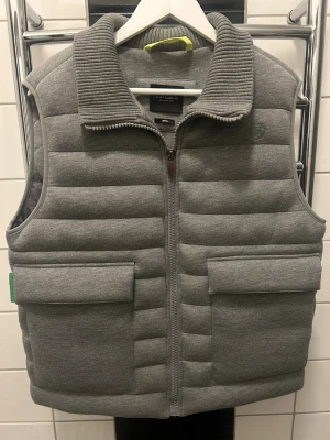 Grå dunväst från Eliasrumelis - Snygg grå dunväst från Stenströms med ribbad krage och två stora fickor framtill. Västen har quiltad design och dragkedja hela vägen upp. Perfekt för lager-på-lager och ger en clean look till din outfit.