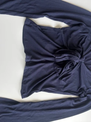 Mörkblå långärmad topp Gina Tricot - Snygg mörkblå långärmad topp från Gina Tricot med knyt framtill. Tillverkad i mjuk bomullsmix och har en croppad passform som ger en trendig look. 