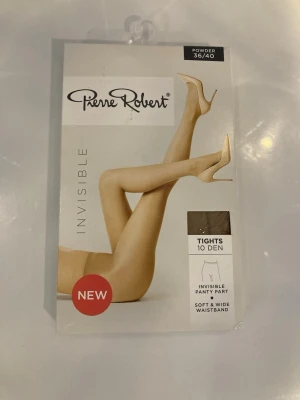 Pierre Robert Invisible Tights 10 den - Säljer ett par tunna, transparenta tights från Pierre Robert i färgen Powder. De har 10 denier, osynlig trosdel och bred, mjuk midjeresår för extra komfort. Perfekta för en naturlig look under klänning eller kjol.