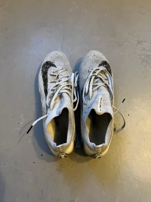 Nike vita Flyknit sneakers - Fotbollsskor med dobbar i bra fungerande skick. Använda och har tydliga spår av användning (se bilder), men inget som påverkar funktionen. Bekväma och stabila på planen, bra grepp. Perfekta för träning eller match. Säljs på grund av att de inte längre används.