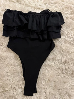 Svart off shoulder body med volanger - Säljer en svart body från Zara med volanger❤️i storlek M men skulle säga att det är mer S