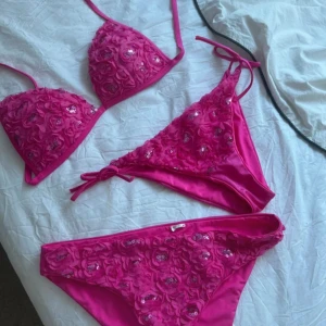 calzedonia bikini - Säljer en superfin rosa bikini med 3D-blommor och paljettdetaljer. Överdelen har trekantsmodell med knyt i nacken och ryggen, och underdelen har matchande blommor och paljetter. Perfekt för dig som vill sticka ut på stranden!