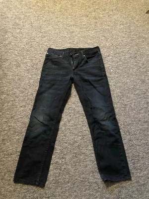 Mörkblå Levi's 501 jeans straight fit - Klassiska mörkblå Levi's 511 jeans med rak passform och fem fickor. Jeansen har knappgylf och är tillverkade i slitstarkt bomullstyg. Perfekta för en avslappnad och tidlös stil.