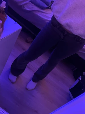 Gråa bootcut Gina tricket jeans - Säljer ett par mörkblå bootcut jeans med   klassisk femficksdesign. Jeansen har en snygg utsvängd passform nedtill och är tillverkade i ett stretchigt denimtyg som sitter bekvämt. Perfekta för dig som gillar en retroinspirerad look.