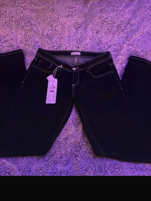 Mörkblå bootcut jeans från Gina Tricot - Snygga mörkblå bootcut jeans från Gina Tricot med vita kontrastsömmar och klassisk femficksdesign. Jeansen har normal midja och är tillverkade i stretchigt denimtyg för en bekväm passform.