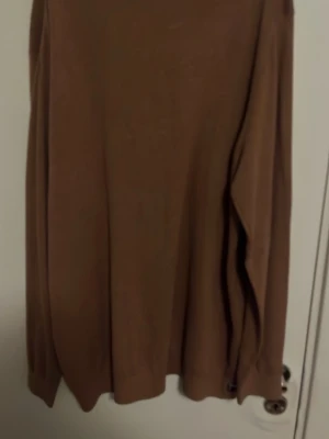 Brun basic sweatshirt - En enkel brun sweatshirt med rund hals och långa ärmar. Tröjan har en avslappnad passform och ribbade muddar vid ärmslut och nederkant. Perfekt för lager på lager under kyliga dagar.