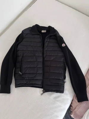 Svart moncler cardigan  - Snygg svart cardigan från Moncler med quiltad framsida, dragkedja och två fickor med zip. Nästan helt ny knappast använd nfc scan på logan såklart Perfekt för lager-på-lager och streetwear. Priset inte hugget i sten 
