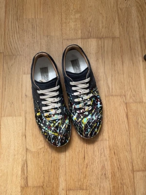 Maison Margiela Gats  - Unika Svarta Paint splatter Gats från Maison Margiela i storlek 43. Skorna passar perfekt till dig som vill sticka ut lite.