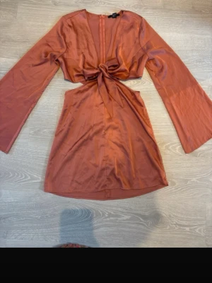 Rosa kort satinklänning - Snygg kort klänning i satin material med långa vida ärmar. Säljer då den inte kommer till användning