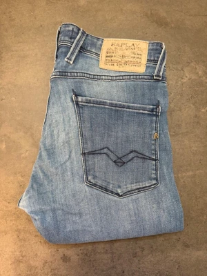 Ljusblå jeans Replay Anbass 32/36 - Säljer ett par ljusblå jeans från Replay med klassisk femficksmodell och raka ben. Jeansen har en snygg tvättad look och detaljerad bakficka med broderi. Perfekta för dig som gillar en avslappnad men stilren stil.