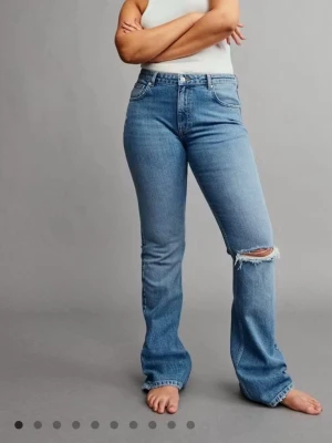 Blå bootcut jeans med hål - Säljer ett par ljusblå bootcut jeans med hål på ena knät. Midwaist, har använt en gång💕