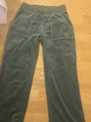 Mörkgröna velour mjukisbyxor - Mörkgröna mjukisbyxor i mjuk velour med bred resår i midjan och dragsko. Stora fickor fram och bakfickor med knappdetaljer. Perfekta för chill dagar och har en relaxed passform.