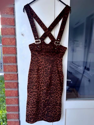 Leopardmönstrad 50-tals rockabilly/pin-up hängselklänning från Collectif, Storlek XS (EU 34) - •Snygg 50-tals/Rockabilly hängselklänning från Collectif (XS)  •Säljer en fantastiskt kurvsmickrande hängselklänning (pinafore) i klassiskt leopardmönster från retromärket Collectif. Designad i tidstypisk 1950-talsstil!  •Klänningen har en hög midja där spännena slutar precis under bysten. Breda axelband som korsas i ryggen. Supersnygg att bära lager-på-lager över en tight topp eller polotröja  •Märke: Collectif Clothing  •Storlek: XS (EU 34)  •Skick: Toppskick, endast använd 1 gång  •Detaljer: 