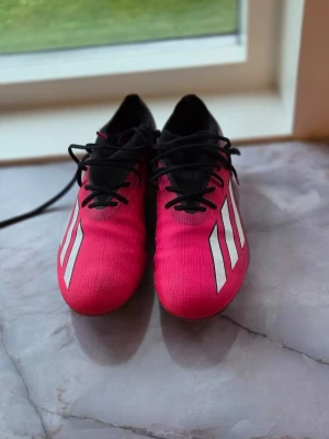 Adidas rosa fotbollsskor med dobbar - Adidas X Speedportal, Snygga fotbollsskor från Adidas i en stark rosa färg med svarta detaljer och vita ränder på sidorna. Skorna har snörning och slitstarka dobbar för bra grepp på planen. Ovandelen är i syntetmaterial och designen är smal och sportig. Ny pris kostar 2759kr. Använda 4 matcher och 4 träningar. Priset ör inte hugget i sten.