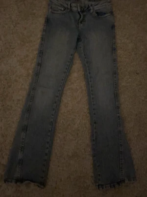 Ljusblå bootcut jeans - Säljer ett par ljusblå bootcut jeans, lite söndriga benslut och klassisk femficksmodell. Jeansen har en lätt tvättad look och detaljerade bakfickor. Perfekta för en avslappnad och trendig stil.