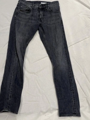 Mörkgrå jeans från Tiger of Sweden - Snygga mörkgrå jeans från Tiger of Sweden med klassisk femficksmodell och raka ben. Jeansen har en diskret tvättad look och patch med logga bak i midjan. Tillverkade i bomull med en stilren och tidlös design.